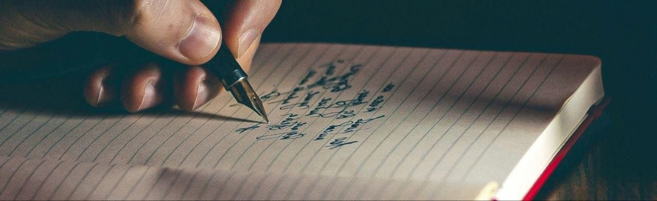 Hand mit Füller schreibt in ein Notizbuch — Tinten-Schrift gut sichtbar, intime Schreib-Atmosphäre